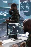 Soldier discussing on phone call in a modern control room, processing real time data and coordinating surveillance efforts. Enhancing national security by supporting decision-making processes. photo