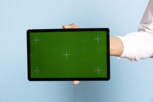 Skilled bellhop holding a tablet with isolated chroma key at the hotel reception, working in hospitality industry and welcoming guests. Five star resort staff shows copy space display. photo