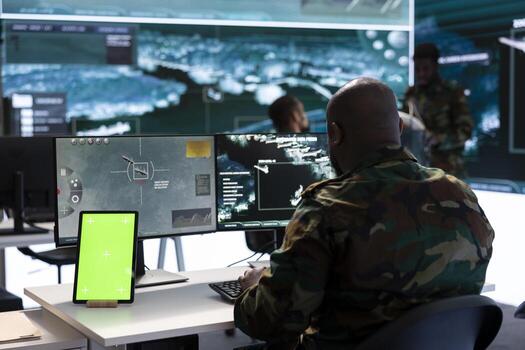 Military man works in command post working on collecting real time data, intelligence gathering activity with surveillance footage for defense mission. Using mockup copy space screen on pc. photo