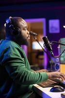Skilled composer producing a new melody with lyrics and piano keys, recording audio files to edit them with mixing console. Young talented artist producer creating soundtracks. photo