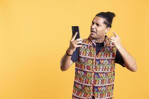 Furious man fighting with friend during videocall, yelling, isolated over studio background. Angry person screaming at mate during teleconference meeting conversation on phone photo