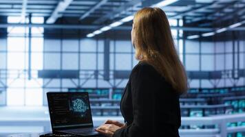 Computer scientist in data center using artificial intelligence computing simulating human brain. IT professional working on notebook with AI machine learning algorithms, camera A photo