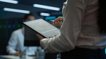 Engineer working in data center used for managing infrastructure rigs energy consumption. Employee using tablet in workplace used for automation and monitoring processes in server farm, camera A photo