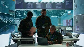 Military personnel in a modern command center handle critical information, collecting live surveillance data to maintain security protocols. Team of army crew working on reconnaissance. Camera B. photo