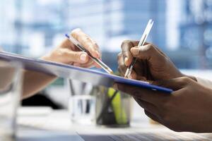 Job interview candidate interested in career advancement, talking with team of HR experts, signing paperwork files. Close up of man writing signature on contract after being hired by recruiter photo