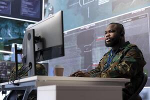 High tech military soldier analyzing real time data for missions, processing intelligence and coordinating strategic operations to ensure national security. Command post tasks with modern gear. photo