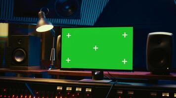 Control room with greenscreen running on computer next to buttons and sliders, multiple controls and switchers on panel board mixing console. Empty professional studio with stereo gear. Camera B. photo
