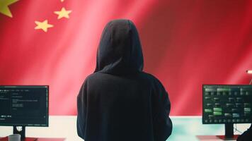 Governmental hacker in high tech office with Chinese flag shown on big screen, IT expert engaged in cyber espionage and criminal activity. Spreading fake news and brainwashing the nation. Camera B. photo