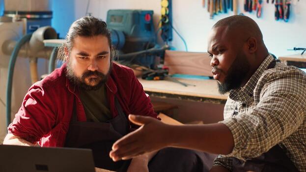 Woodworkers using CAD software on laptop to design wooden objects, pointing towards screen. Carpenters using program on notebook to help them do furniture assembling in joinery, camera A photo