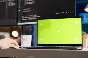 System administrator designing and developing software applications using green screen laptop. Tech support expert implementing and maintaining company systems using chroma key device photo