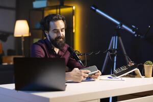 Happy content creator doing technology review of wireless portable speaker for internet platforms channel. Cheerful influencer presenting music playing gear to his subscribers photo