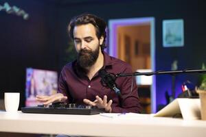 Artist filming DJ mixing tutorial, showing examples of sampling on sound controller to audience. Viral internet star showing modern musical equipment to subscribers in home studio photo