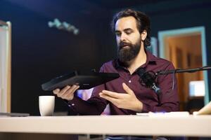Content creator filming technology review of newly released DJ controller, unboxing it and presenting specifications to audience. Influencer showing sound mixer equipment to followers photo