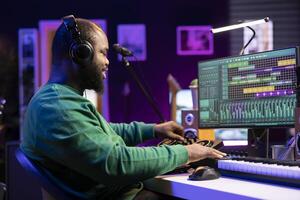 Audio technician editing tunes on mixing console to adjust volume levels, twisting pre amp knobs in home studio. Composer producing new music with professional stereo equipment. photo