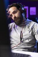 Professional gamer interacting with fans during livestream, disappointed after losing esports match. Man streaming in studio, unhappy with being defeated in online multiplayer videogame photo