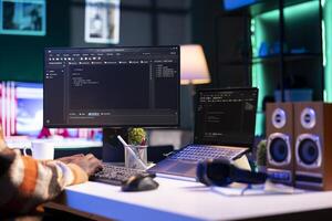 Black programmer remotely working in home office writing code on computer at his desk. Programming engineer IT expert in apartment typing lines of code at workstation, teleworking. photo
