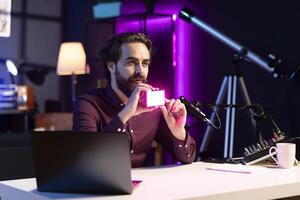 Reviewer discussing with viewers about mini led lights during live broadcast on internet. Influencer chatting with fans during stream, filming RGB lighting device in studio photo