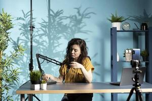 Influencer turning knobs on sound mixer, ensuring microphone captures clear audio for upcoming , filming with selfie cellphone camera. Woman checking audio levels, recording with mobile phone photo