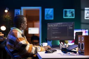 Black software engineer writes complex binary code scripts on computer, cybersecurity. Teleworking IT specialist in home office using programming language to safeguard consumer data. photo