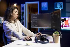 Computer scientist doing software debugging on PC at home, checking broken lines of code displayed on monitors. Skilled IT expert in apartment fixing coding problems, typing on keyboard photo