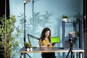 Smiling woman in studio filming tech tutorial on how to do maintenance on mockup broken tablet. Cheerful online show host teaching subscribers how to open and fix isolated screen digital device photo