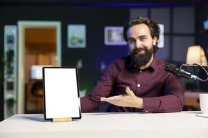 Portrait of happy influencer in studio filming mockup tablet review for tech enthusiasts. Joyful media star hosts technology internet show, unboxing isolated screen digital portable device photo