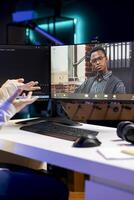 IT professional working from home in videocall with coworker, testing and deploying programs and systems. Admin checking code with colleague in teleconference, sitting at desk chair in apartment photo