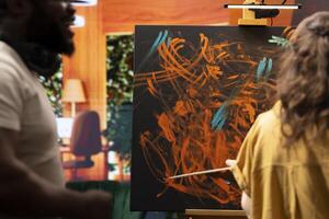 Team of artists in a gallery atelier working on a new art piece, using the finger painting technique for an abstract creation. Blending acrylic paints with precision to create a contemporary design. photo