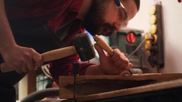 Artisan using bench vise to hold timber block, carving intricate designs into wood using chisel and hammer. Artist uses vice tool to clamp piece of wood, shaping log with tools, camera A close up shot photo