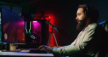 Pro gamer competing in intense online multiplayer videogame with his friends, shooting enemies from living room with rgb lights. Man using gaming computer and headphones for immersive experience photo