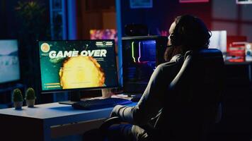 Upset gamer hitting desk in frustration after receiving game over screen, getting his spaceship destroyed in flying game. Sad player feeling disappointed after losing science fiction videogame photo