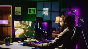 Man in dark living room playing science fiction videogame on gaming PC, relaxing by shooting enemies. Gamer battling flying robots in online singleplayer shooter from rgb lights ornate house photo
