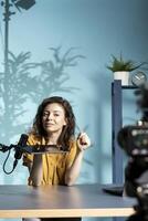 Upbeat tech engineer presenting tablet in entry level low budget price range, filming from dimly lit home studio. Jolly tech content creator reviewing digital device in front of online audience photo