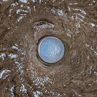 A circular hole in the ground with a blue sky photo