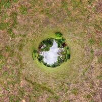 A circular view of a grassy field with a house in the middle photo
