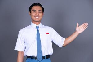 Indonesian Male High School Student in Uniform Presenting Gesture And Smiling Background photo