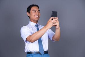 Indonesian Male High School Student in Uniform Smiling While Holding Phone And Smiling photo