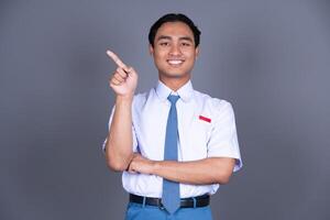 Indonesian Male High School Student in Uniform Smiling While Pointing Finger photo