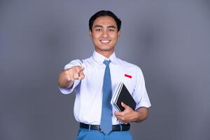 Indonesian Boy High School Student in Uniform Smiling While Pointing Finger photo