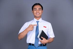Indonesian Boy High School Student in Uniform Smiling While Pointing Finger Background photo