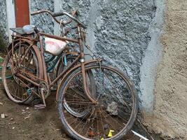 Two rusted bicycles leaning against a weathered wall, capturing a nostalgic scene of bygone days. The image highlights the beauty in decay and the charm of vintage transportation. photo