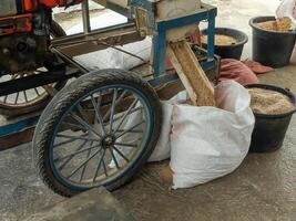 A traditional milling cart processes rice, funneling them into sacks and buckets. The scene captures the essence of rural agriculture, combining manual effort with simple machinery. photo