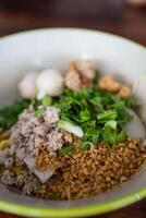 Egg yellow noodles topping with minced pork, peanuts, crispy pork rinds and fish meatball. photo