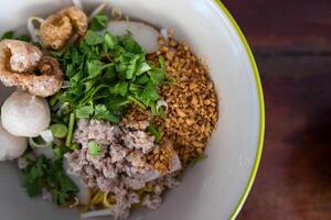 Egg noodles topping with minced pork, peanuts, crispy pork rinds and fish meatball photo