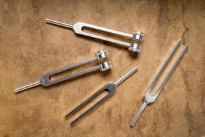 Weighted and unweighted metal tuning fork used for tuning musical instruments, sound therapy, chakra healing or relaxation. photo