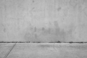 black and white urban texture and background - old gray grunge building wall and concrete pavement photo