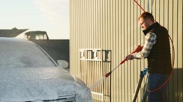 Man Using Pressure Washer to Clean a Car with Soap Foam video
