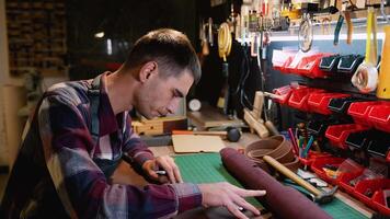 A skilled craftsman works meticulously on a leather sheet, preparing for a precise cut video