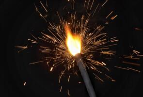 A sparkler is lit with a black background photo