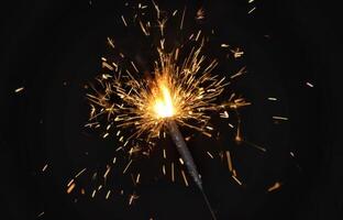 A sparkler is lit on a black background photo